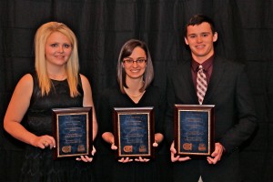 Three students holding up award plaques.