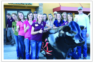 Group of students standing outside a restaurant with their thumbs up.
