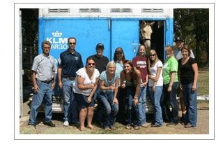 Group of people in front of a horse trailer.