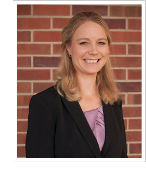 Erin Morrow Hawley standing in front of a brick background.