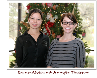 Bruna Alves, left, and Jennifer Thorson. They are standing in front of a Christmas tree.