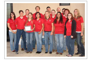 Group of people in red shirts standing with an award.