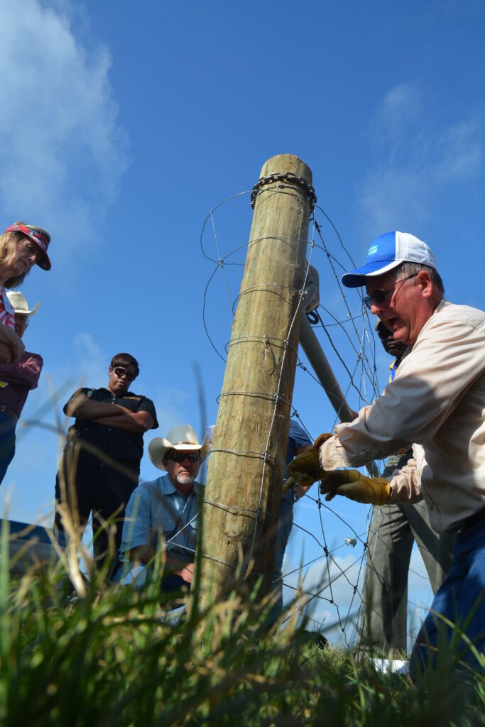 A man demonstrating fence building skills at an event.