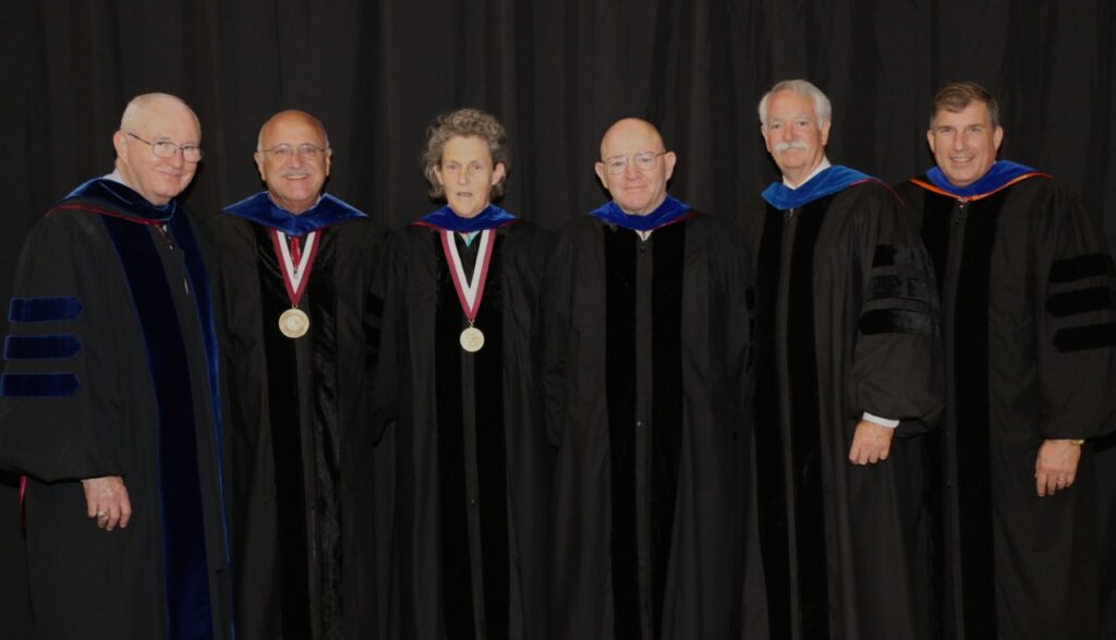 Dr. Temple Grandin, center, with Dr. Russell Cross, Dr. Jeff Savell, Dr. Dr. Gary Smith, Dr. Kevin Pond, and Dr. Dan Hale. They are all wearing academic regalia.