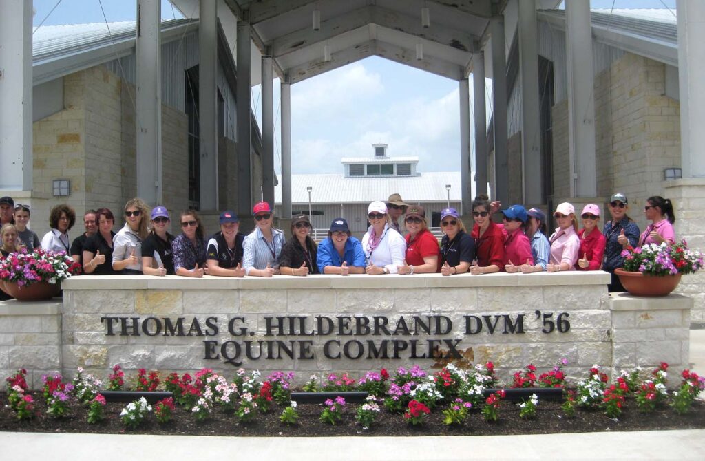Australian students standing behind the Hildebrand Equine Complex sign.