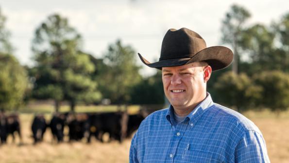 Ryan Reuter standing in a pasture with cattle in the background.