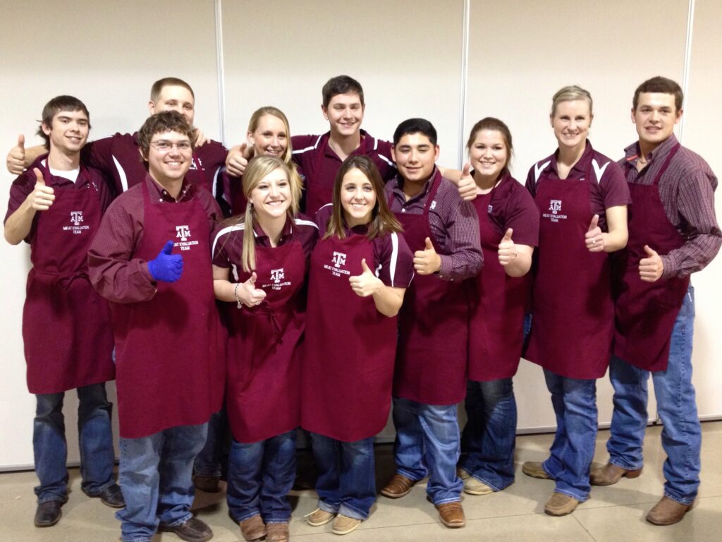 The meat judging team standing with the "Gig 'em" thumb.