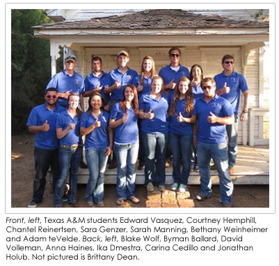 Students wearing blue shirts in front of an old house.
