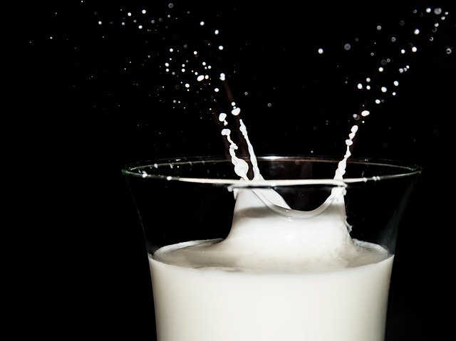 A glass of milk with part of it being splashed upwards.