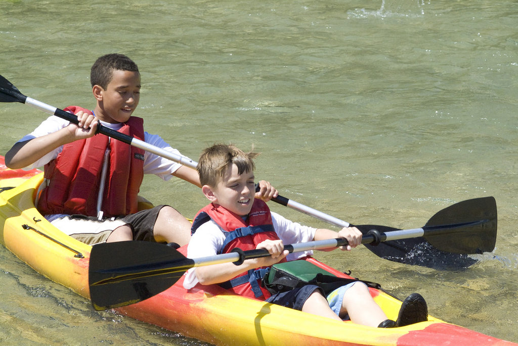 Two children in a kayak rowing.