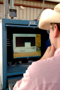 A person looks at a computer monitor at a ranch.