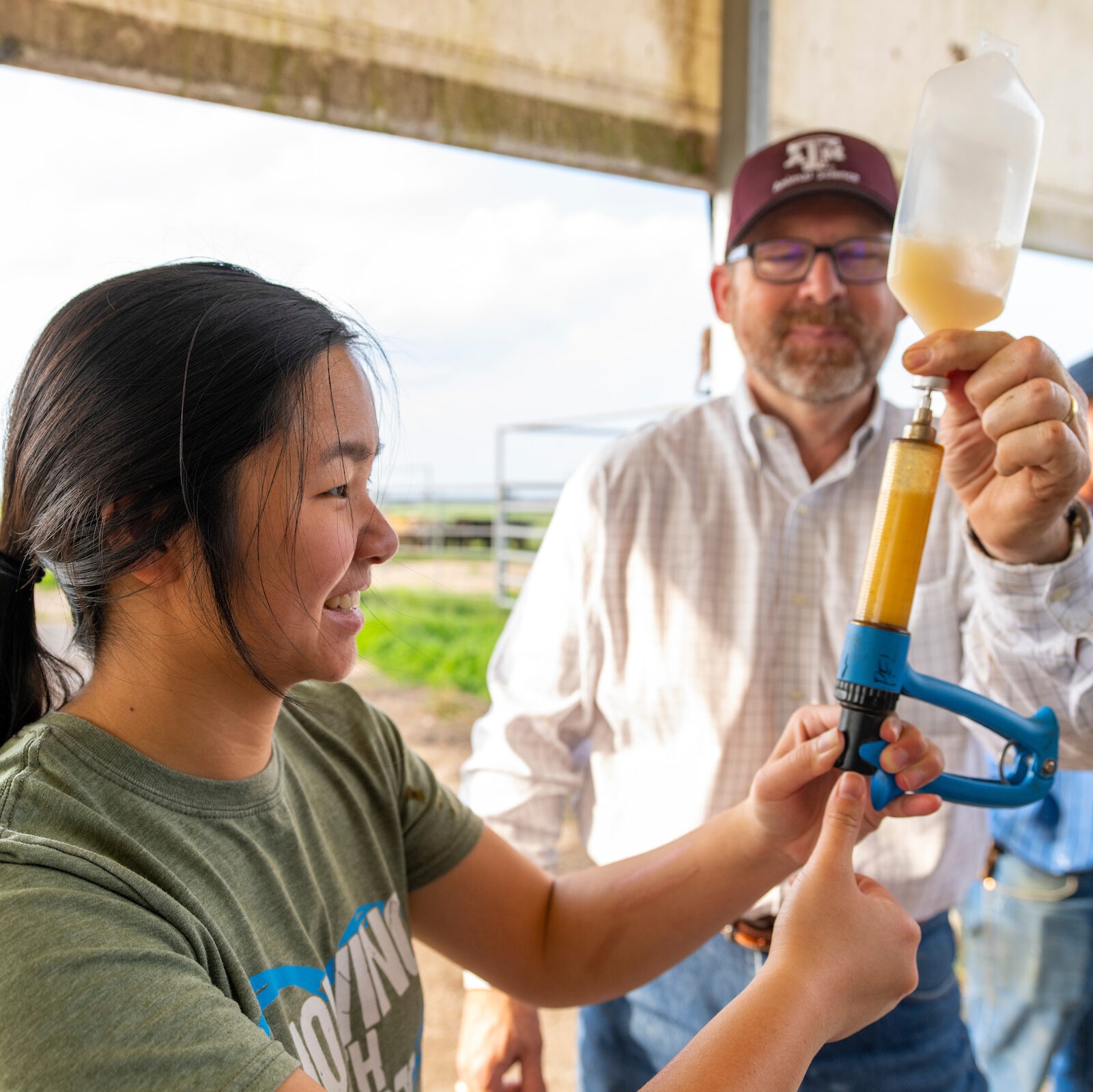 Student and professor learning how to use animal science equipment out on the field. 