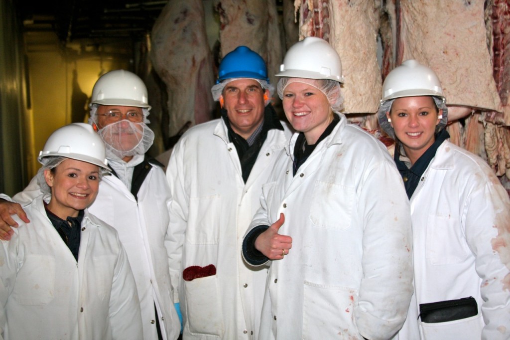 Five beef auditors in white coats and hard hats posing as a group