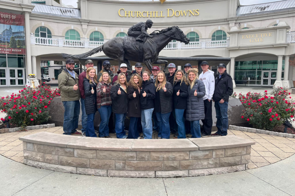 The Texas A&M Livestock Judging Team standing in front of a horse statue at Churchill Downs.