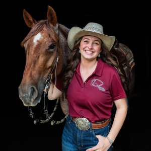 Charlie Proctor standing for a headshot of her and her horse. 