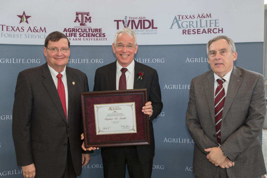 Dr. Stephen B. Smith, center, with his award. Standing with Smith is  Dr. Mark Hussey, vice chancellor and dean of agriculture and life sciences at Texas A&M, left, and Dr. Craig Nessler, director of Texas A&M AgriLife Research.
