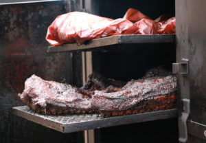 Brisket being cooked in a pit.