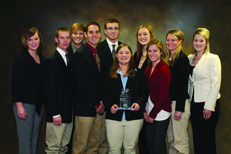 Group of people with the center woman holding an award plaque.