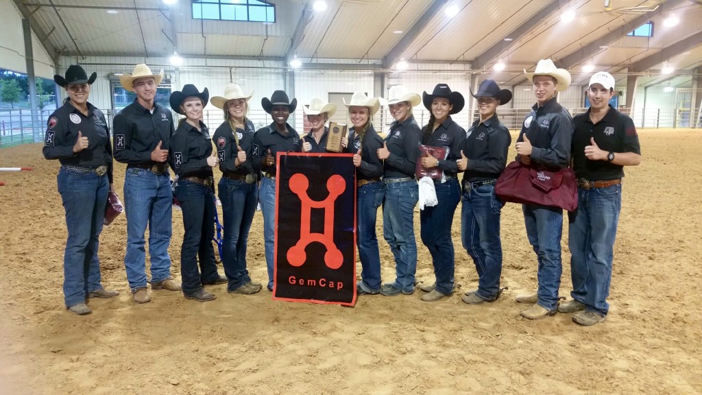 Group standing with their thumbs up behind a sign.