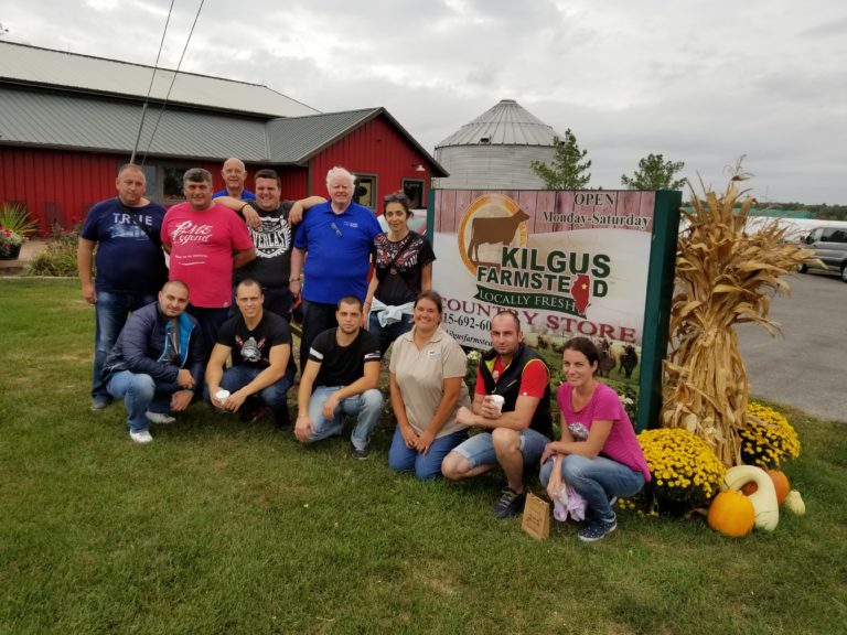 Bulgarian dairy farmers next to a Kilgus Farmstead sign.