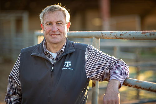 Dr. G. Cliff Lamb standing by a pipe fence.