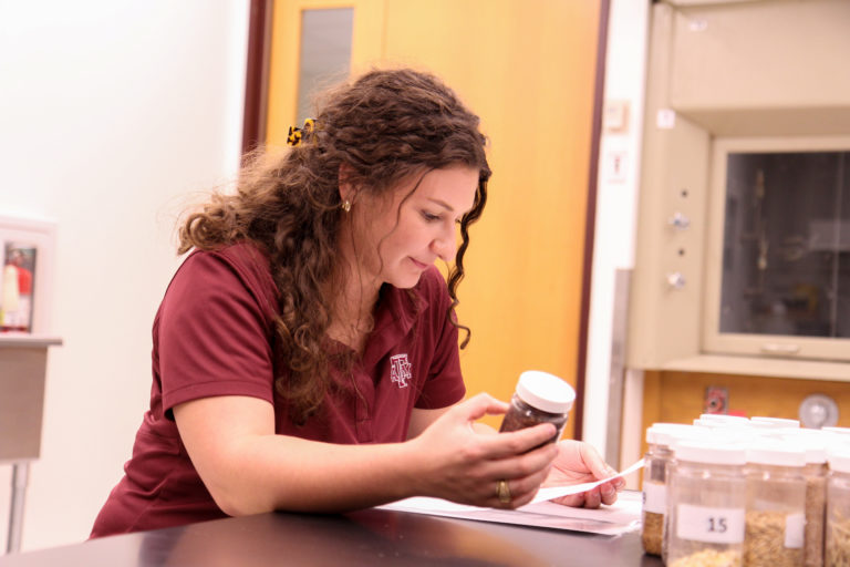 Alyson looking at a bottle of feedstuff prior to teaching ANSC 318 lab.