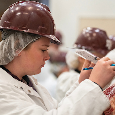 A student on the meat judging team writes on a clipboard.