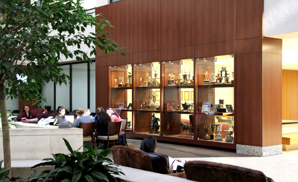 A large wooden trophy case facing tables with students sitting and studying.