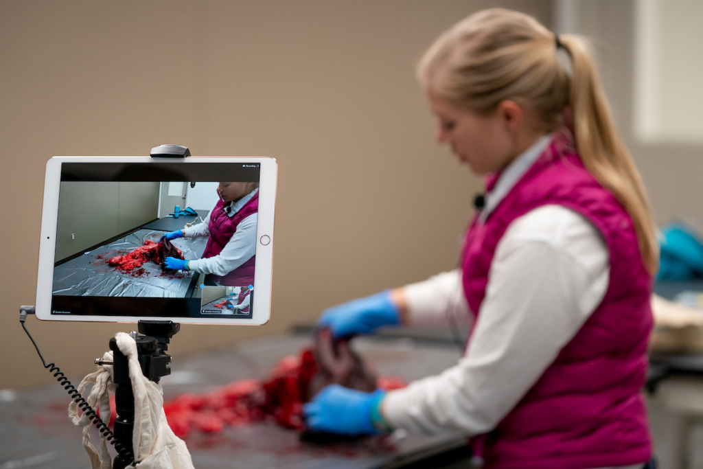 Woman being filmed giving a demonstration in a lab.