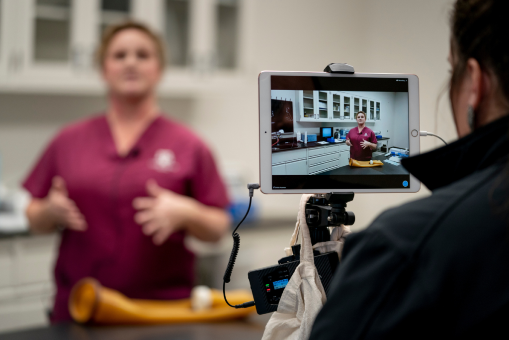 Woman filming another woman talking and giving demonstration in a lab.