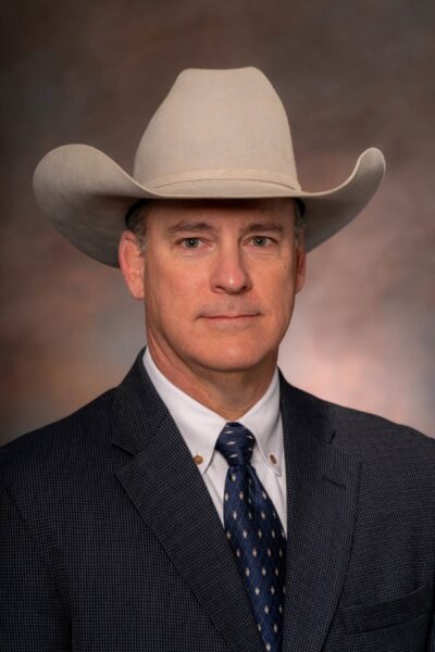 Headshot of Clay Mathis, head of the Animal Science Department, wearing a suit and tie with a cowboy hat.