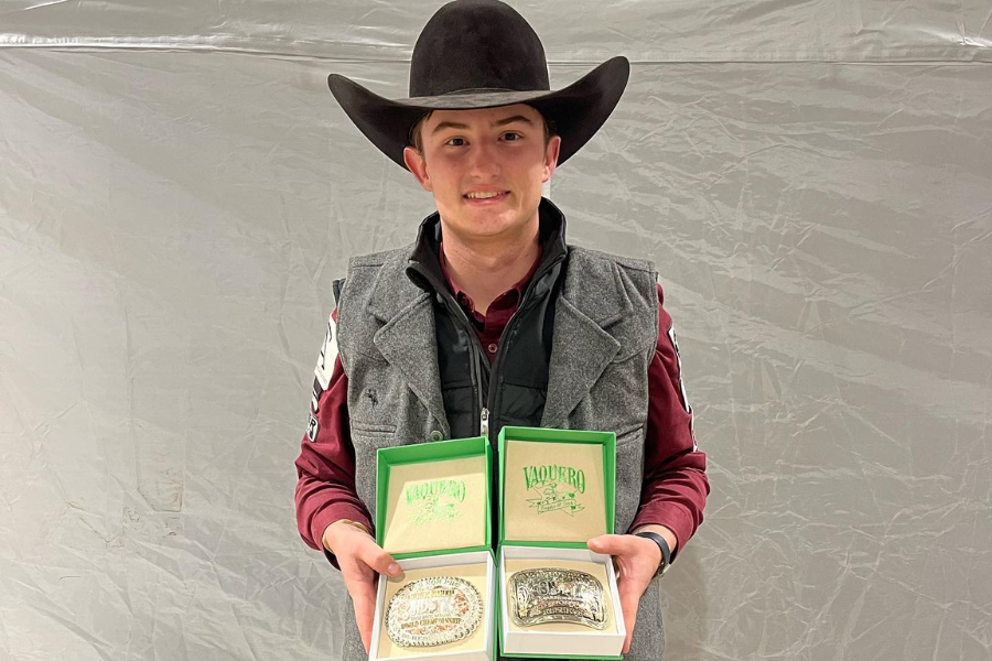 student posing with awards