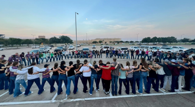 Campers stand in circle with arms around each other.