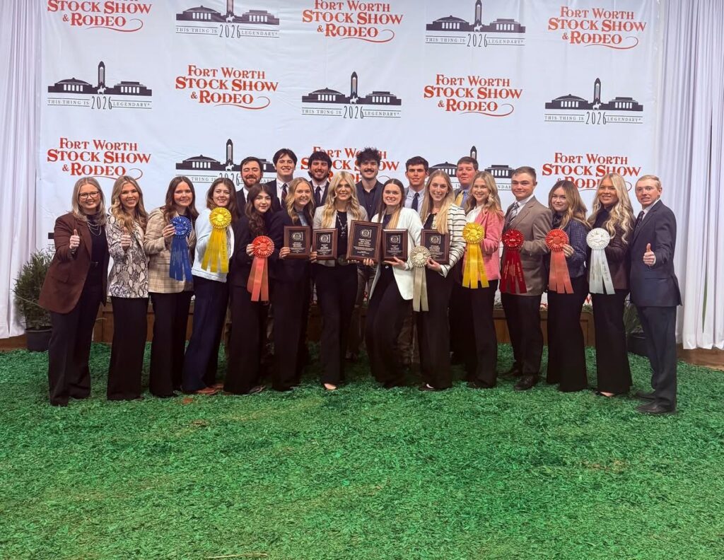 The 2026 Fightin' Texas Aggie Meat Judging Team. They are posing for a photo in western business attire and holding ribbons and plaques.